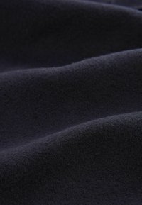 Tela de un oscuro color navy con una superficie suave y texturizada, que presenta suaves ondas y fibras sutiles, diseñada para la comodidad y versatilidad.
