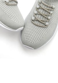 Hellgraue Sportschuhe mit einem atmungsaktiven Strick-Obermaterial, dekorativen Schnürsenkeln und weißen Gummi-Sohlen, die eine strukturierte Oberfläche zeigen.