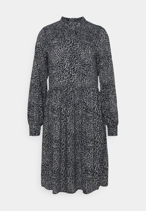 Langärmliges Kleid aus schwarzem Stoff mit einem weißen Blättermuster, ausgestattet mit einem hochgeschlossenen Hals und einer gerafften Taille, endend in einem ausgestellt geschnittenen Rock.