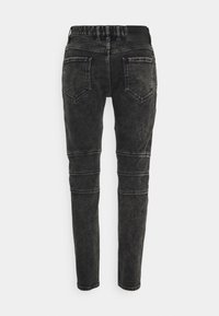 Černé skinny džíny z denimu s vybledlým vzhledem, předními a zadními kapsami a detaily šití pro odvážný design. Nastavitelný pas.