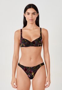 Zwarte bloemenkant lingerie set, bestaande uit een balconette bh met brede bandjes en een bijpassende string, beide versierd met kleurrijke borduursels.