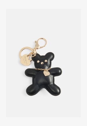 Portachiavi a forma di orso in pelle nera con hardware dorato, caratterizzato da occhi rotondi, un ciondolo a forma di cuore e dettagli cuciti lungo i bordi.