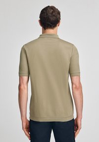 Kortärmad polo-shirt i en ljus khaki färg, tillverkad av mjuk bomull. Har en klassisk krage och en rak fåll. Enkelt och rent design.