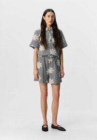 Kortärmad rutiga blus med blommönster, matchad med kortbyxor. Outfiten har en avslappnad passform och elastisk midja.