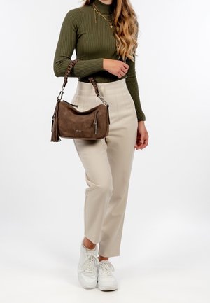 Hnědá semišová kabelka s pletenou rukojetí, kapsou na zip a ozdobou střapcem, doplněná krémovými kalhotami s vysokým pasem a bílými teniskami.
