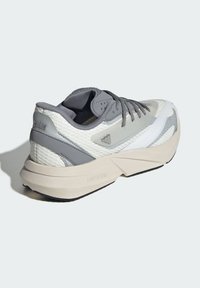 Harmaa ja valkoinen urheilusandaali, jossa on teksturoidusta verkosta valmistettu päällinen, sileät korostukset, paksu beige pohja ja sivussa "LIGHTSTRIKE" -logo.