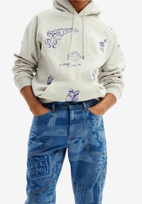 Gray hoodie with purple graphic prints including characters and text. Paired with blue patterned denim jeans featuring various textures and designs.