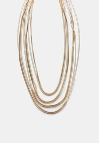 Necklace višestrukih niti zlatnog tona s glatkim, fleksibilnim metalnim lancima, koji imaju različite dužine i stvaraju slojeviti efekt.