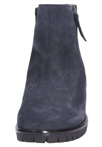 Granatowy zamszowy botek za kostkę z masywną czarną podeszwą, z bocznym zamkiem błyskawicznym i małym frędzelkiem na górze.