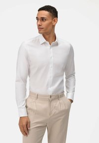 Witte overhemden met lange mouwen, met een button-down kraag en een gladde textuur. Gecombineerd met lichtbeige broeken met een platte voorkant.