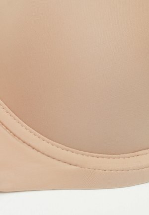 Nude-färgad bh-kupa tillverkad av slät tyg med en lätt lyster, med en böjd söm och detaljerad sömnad längs kanten.