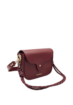 Sac bandoulière en cuir rouge foncé avec fermoir doré, bordure tressée et anse en corde à motifs, portant l'inscription "Craie Studio" à l'avant.