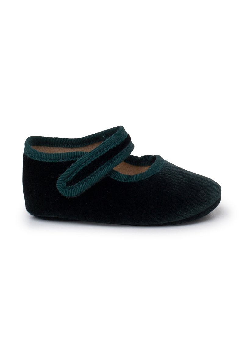Zapato de terciopelo negro con correa verde, punta redondeada, textura suave y plantilla acolchada. Presenta una suela plana para mayor comodidad.