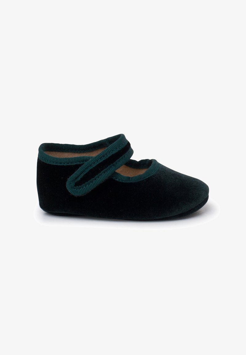 Zapato de terciopelo negro con correa verde, punta redondeada, textura suave y plantilla acolchada. Presenta una suela plana para mayor comodidad.