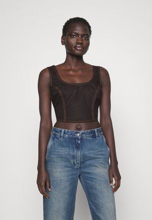Top en denim noir court avec encolure dégagée et coutures orange contrastantes, associé à un jean taille haute bleu clair.