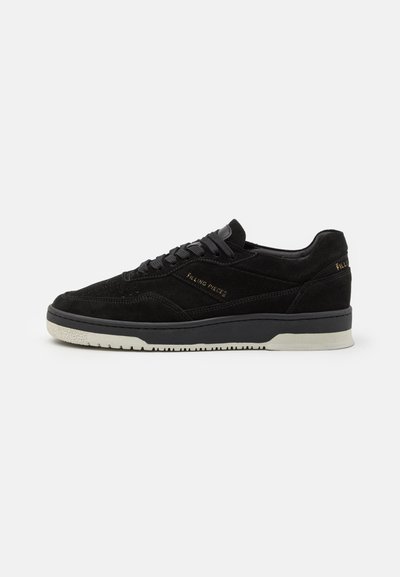 Black suede sneakers with a textured finish, featuring a black rubber sole, contrasting white midsole, and gold branding on the side.