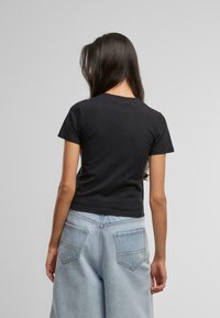 Svart bomulls t-skjorte med korte ermer, tett passform og rund hals, kombinert med høylivet lyse denim bukser med vid ben.