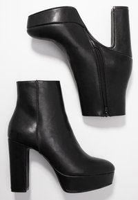 Black faux leather ankle boots with a high platform, chunky heel, and side zipper. Smooth texture and rounded toe.