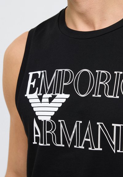 Μαύρο βαμβακερό τοπ χωρίς μανίκια με μεγάλο λευκό κείμενο «Emporio Armani» και γραφικό με το λογότυπο αετού στο στήθος.