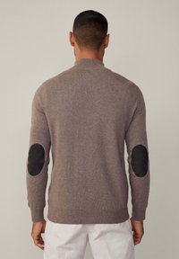 Maglione in misto lana marrone con collo alto, maniche lunghe e toppe in suede nero sui gomiti. I polsini e l'orlo a costine arricchiscono il design.