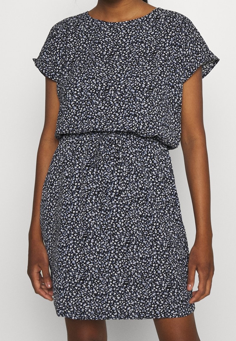 Robe fleurie bleu marine avec des manches courtes, taille froncée et coupe ample. Présente de petits motifs de fleurs blanches et bleu clair sur l'ensemble.