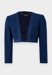 Zkrácený námořnický modrý blazer s dlouhými rukávy, volným předním dílem a jemným prošíváním na jednobarevném bílém pozadí.