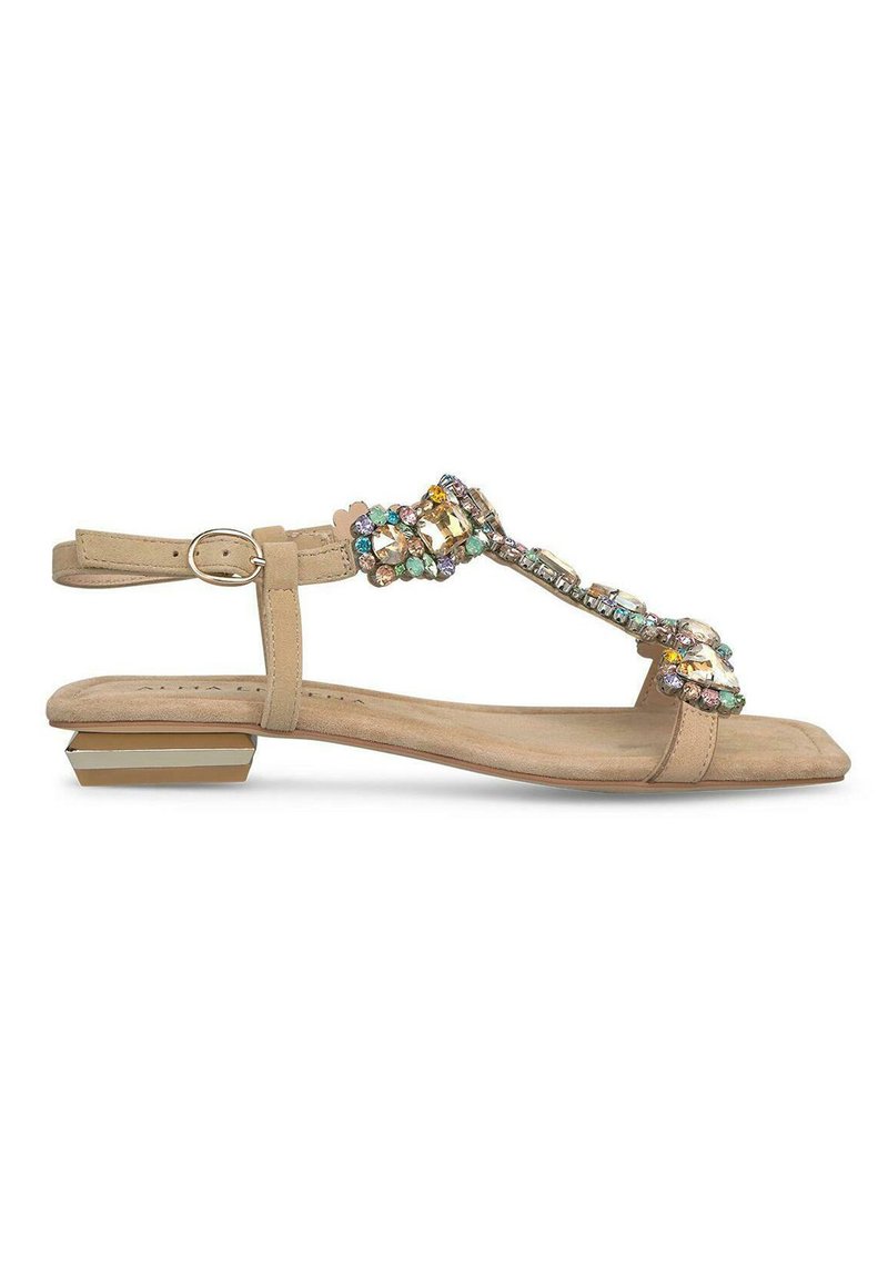 Sandalo beige con suola piatta, cinghia decorata con pietre multicolori e un accento metallico rettangolare sul tallone.