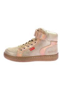Zapatilla alta hecha de material sintético dorado metálico, con acentos en color beige, parte delantera con cordones, tira de velcro y suela de goma texturizada.