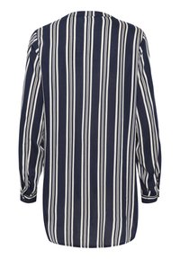 Camisa azul marino con rayas blancas verticales, de mangas largas y con dobladillo redondeado. Fabricada en tejido ligero. Detalle de botones en los puños.