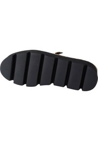 Suela de zapato negra con una textura estriada, que presenta seis surcos prominentes y un borde liso. Fabricada de un material de goma duradero.