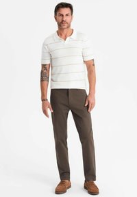 Polo à manches courtes rayé en blanc avec des rayures beiges, associé à un pantalon texture marron et des chaussures à lacets marron.