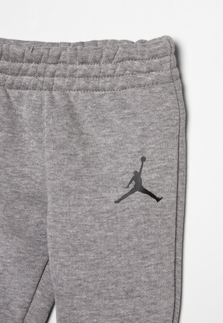 Pantalons de survêtement gris en tissu doux avec une taille côtelée. Présente un logo noir Jordan sur le côté.