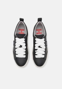 Schwarze Lederturnschuhe mit weißen Schnürsenkeln, runder Spitze und Gummisohle. Mit Logo auf der Zunge und der Seite, und roten Akzenten im Inneren.