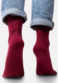 Burgundowe skarpety prążkowane o gładkiej fakturze, z konstrukcją do połowy łydki i zrolowanym mankietem dżinsowym, uwydatniającym kolor skarpet.