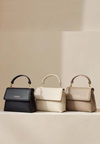 Trois sacs à main structurés : noir, crème et marron clair. Fabriqués en cuir texturé avec des poignées supérieures et des accents en métal doré.