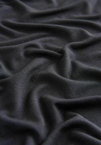 Soft black fabric with visible knit texture and gentle folds creating uneven surface and subtle shadows.