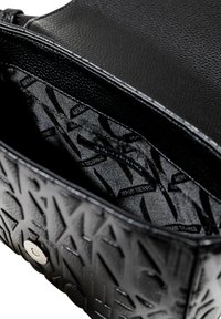 Borsa a tracolla in pelle nera texture con un design del logo impresso. L'interno è foderato in tessuto liscio con un motivo a logo ripetuto.