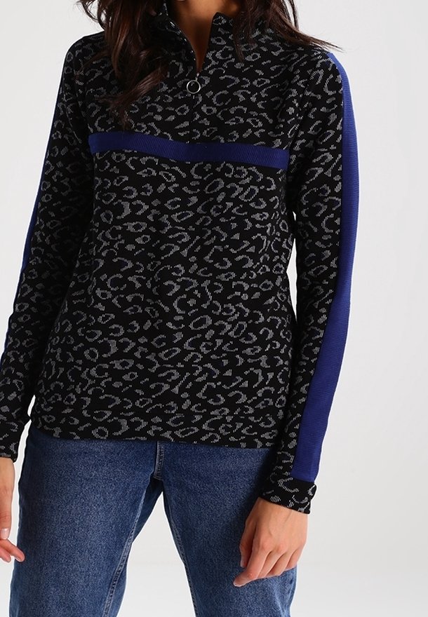 Suéter negro con un patrón de leopardo, presenta un cuello con cremallera y acentos azules en las mangas. Fabricado con un tejido texturizado.