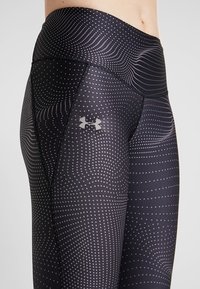 Leggings sportivi neri con un motivo testurizzato di punti e linee ondulate, con un logo argentato di lato e un design a vita alta.