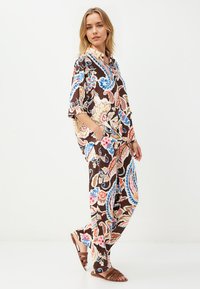 Braunes floral gemustertes Kleidungsstück mit kurzen Ärmeln, lockeren Hosen und einem Kragen, akzentuiert mit Blau, Pink und Creme.