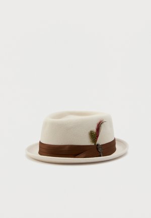 Crème-kleurige vilten fedora met een bruine lintenband en decoratieve rode en gele veren op een witte achtergrond.