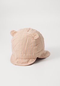 Striped cap with soft, textured fabric in peach and cream, featuring small ear accents and a curved brim.