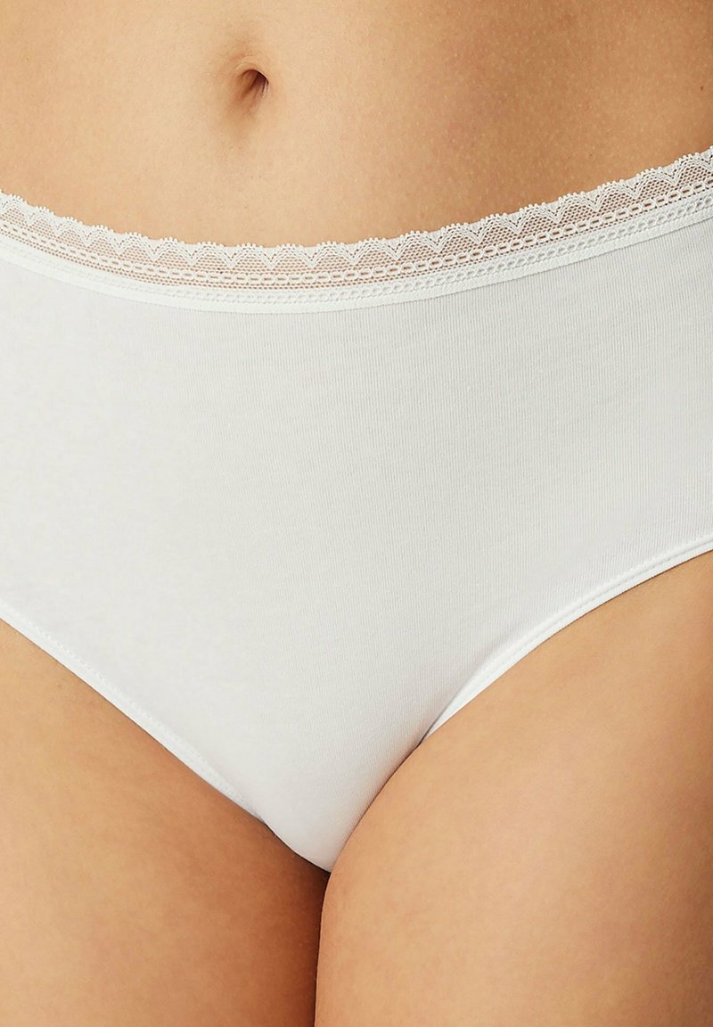 Slip di cotone bianco con una texture liscia e un delicato bordo in pizzo lungo l'elastico in vita. Presenta un classico taglio a vita alta.