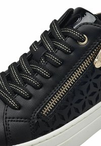 Sneaker nera in pelle con lato testurizzato, motivo decorativo, cerniera argentata e lacci neri a contrasto con accenti argentati. Suola bianca.