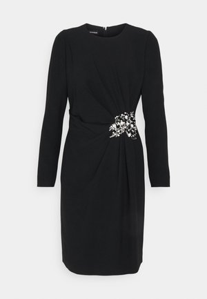 Black dress with long sleeves, a round neckline, and a gathered design. Features a floral embellishment at the waist with bead accents.