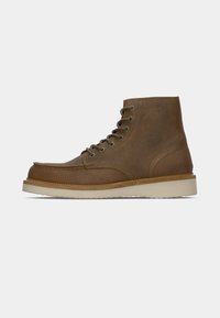 Stivale alla caviglia in suede marrone con suola beige, dettagli cuciti e punta arrotondata visto dal lato esterno.