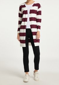 Maroon and white striped long cardigan made of soft knit material, open front design, worn over a white top and black pants, with casual shoes.