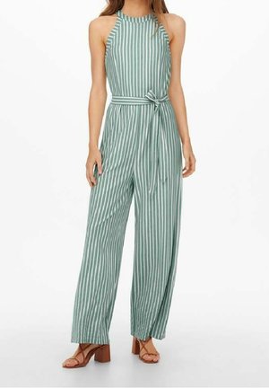 Zielony kombinezon w paski z dekoltem na halter, z paskiem w talii, szerokimi spodniami i teksturowanym materiałem. Połączony z brązowymi sandałami na słupku.