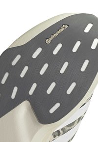 Schuhsohle aus schwarzem Gummi mit länglichen ovalen Ausschnitten und einem kleinen "Continental"-Logo nahe der oberen Kante.