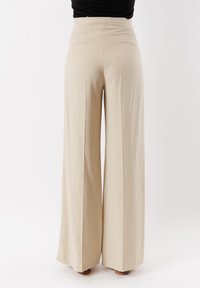 Pantaloni beige a gamba larga con vita alta, realizzati in tessuto morbido, con una texture liscia e senza motivi o dettagli visibili.